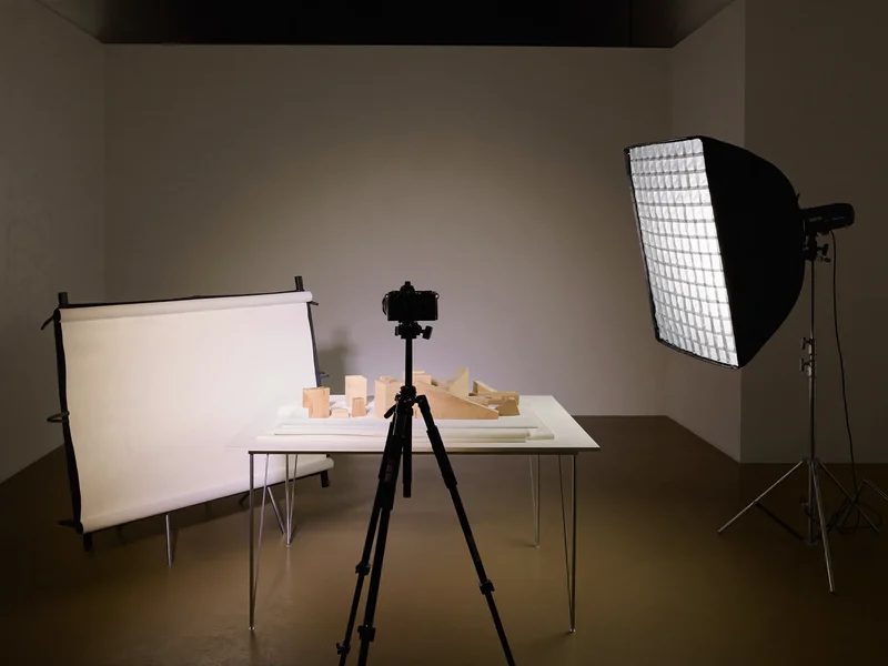 Set de studio văzut din spatele aparatului, cu trepied, reflector alb și softbox